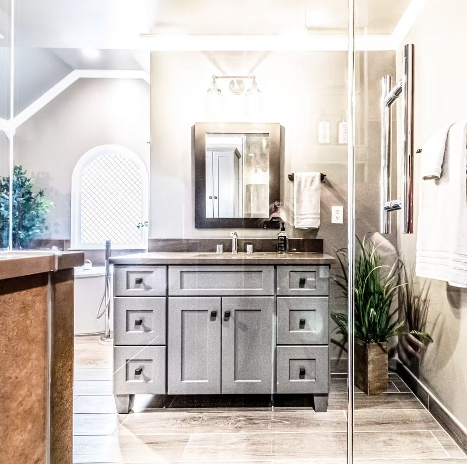 Bright modern bathroom with gray vanity, mirror, and white towel accents