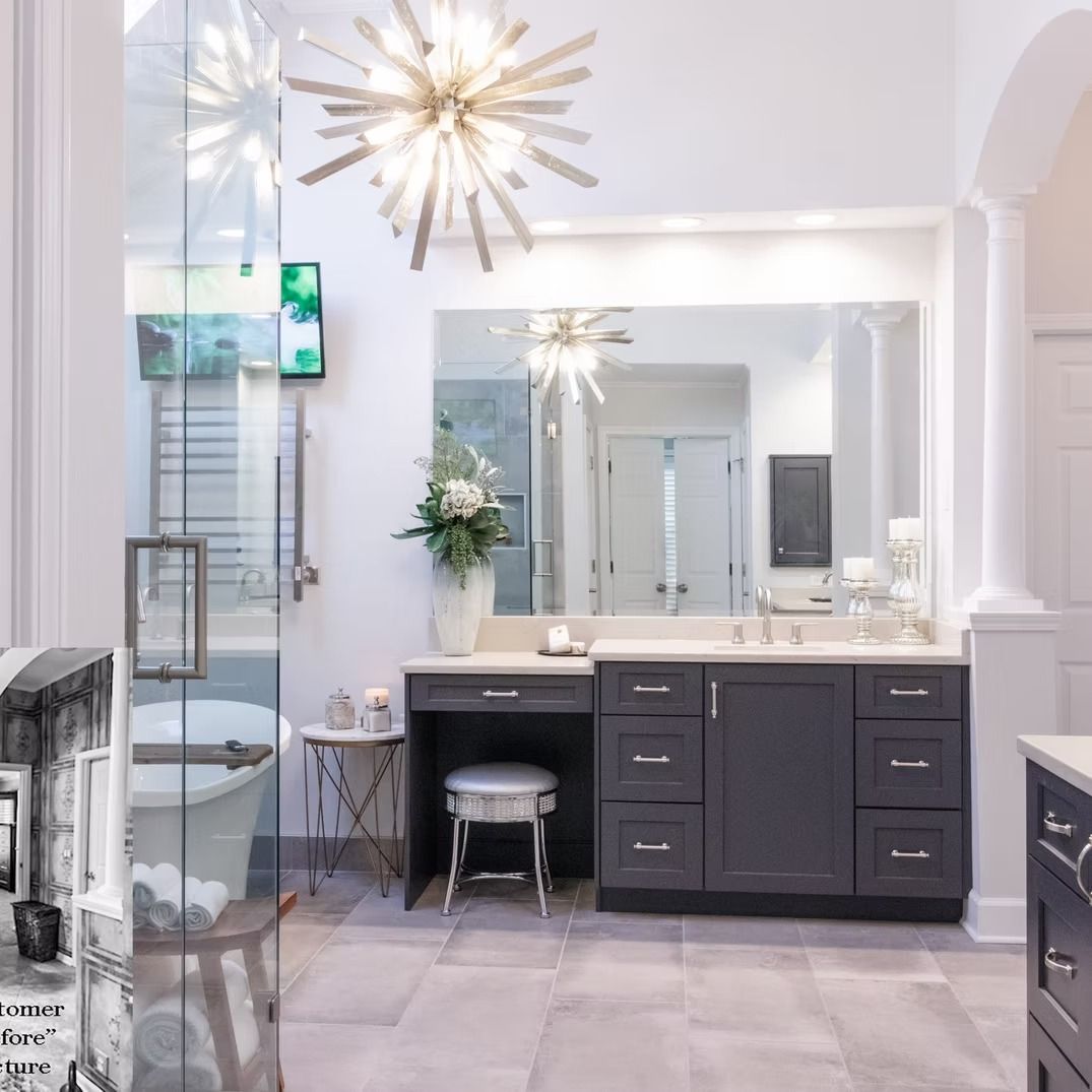 Bright modern bathroom with white walls, dark vanity, large mirror, and starburst light fixture