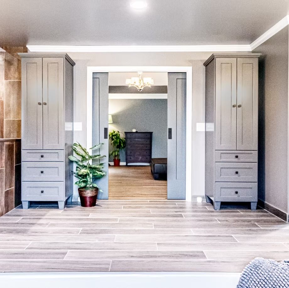 Modern living room entrance with gray built-ins, potted plant, and doorway to a fireplace area