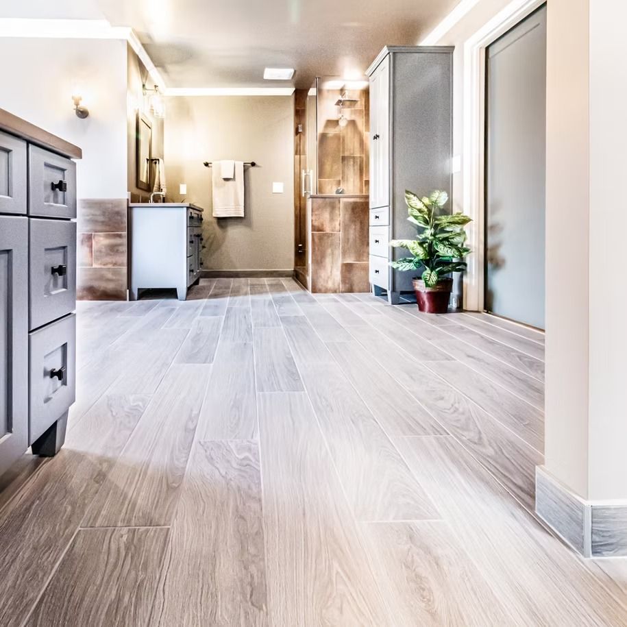 Bright modern hallway with light wood floors, white walls, cabinets, mirror, and a potted plant