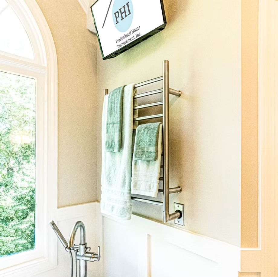 Towel rack with green towels on a beige bathroom wall beside a window and sink faucet
