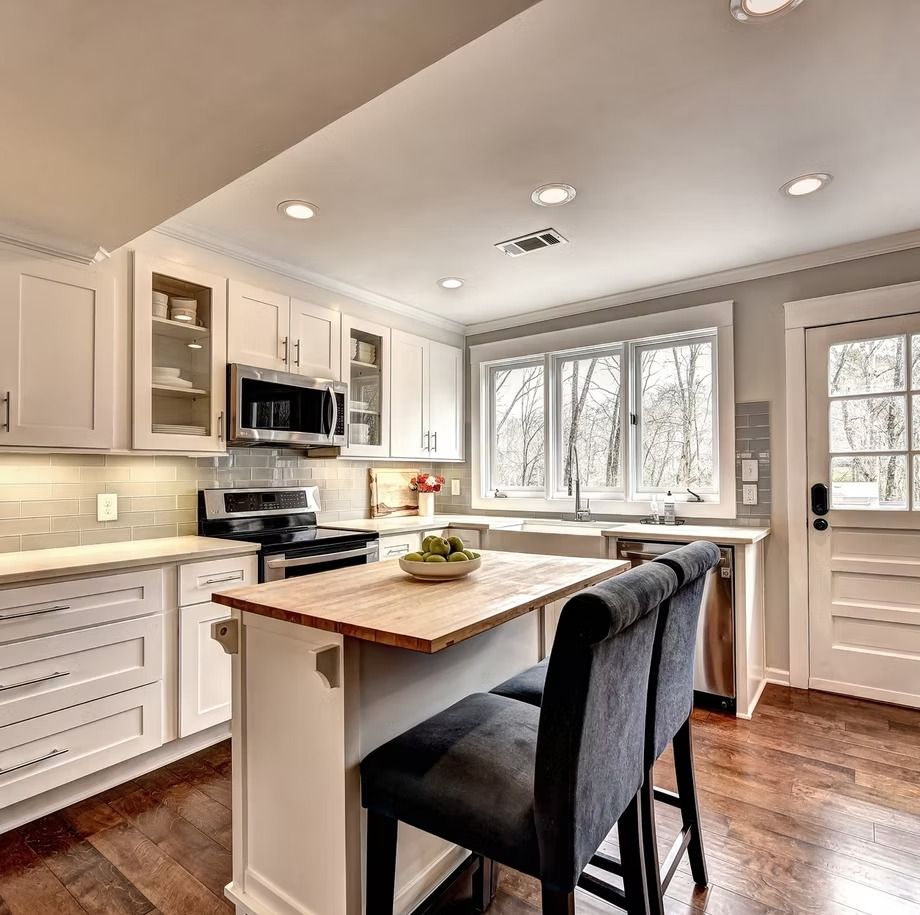 Bright modern kitchen with white cabinets, wood island, and large windows