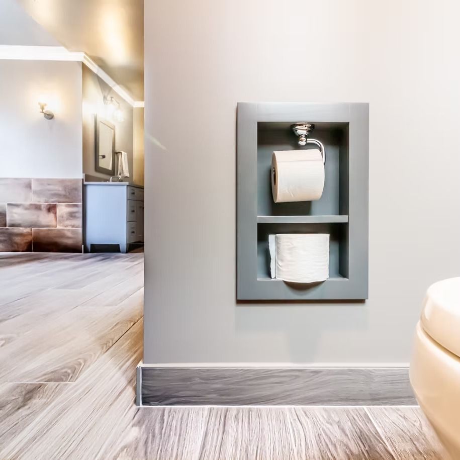 Wall-mounted toilet paper holder with two rolls in a bright bathroom hallway