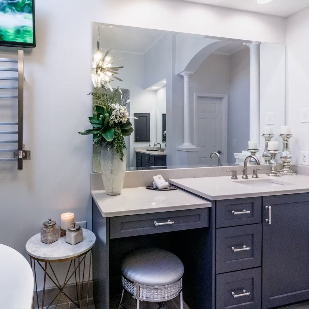 Modern bathroom vanity with mirror, white sink, gray cabinets, and decorative accents