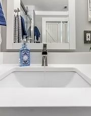 Modern bathroom sink with mirror, soap dispenser, and folded blue towel reflections