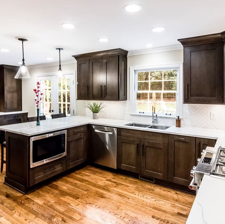 Bright modern kitchen with dark wood cabinets, white counters, stainless sink, and hardwood floors