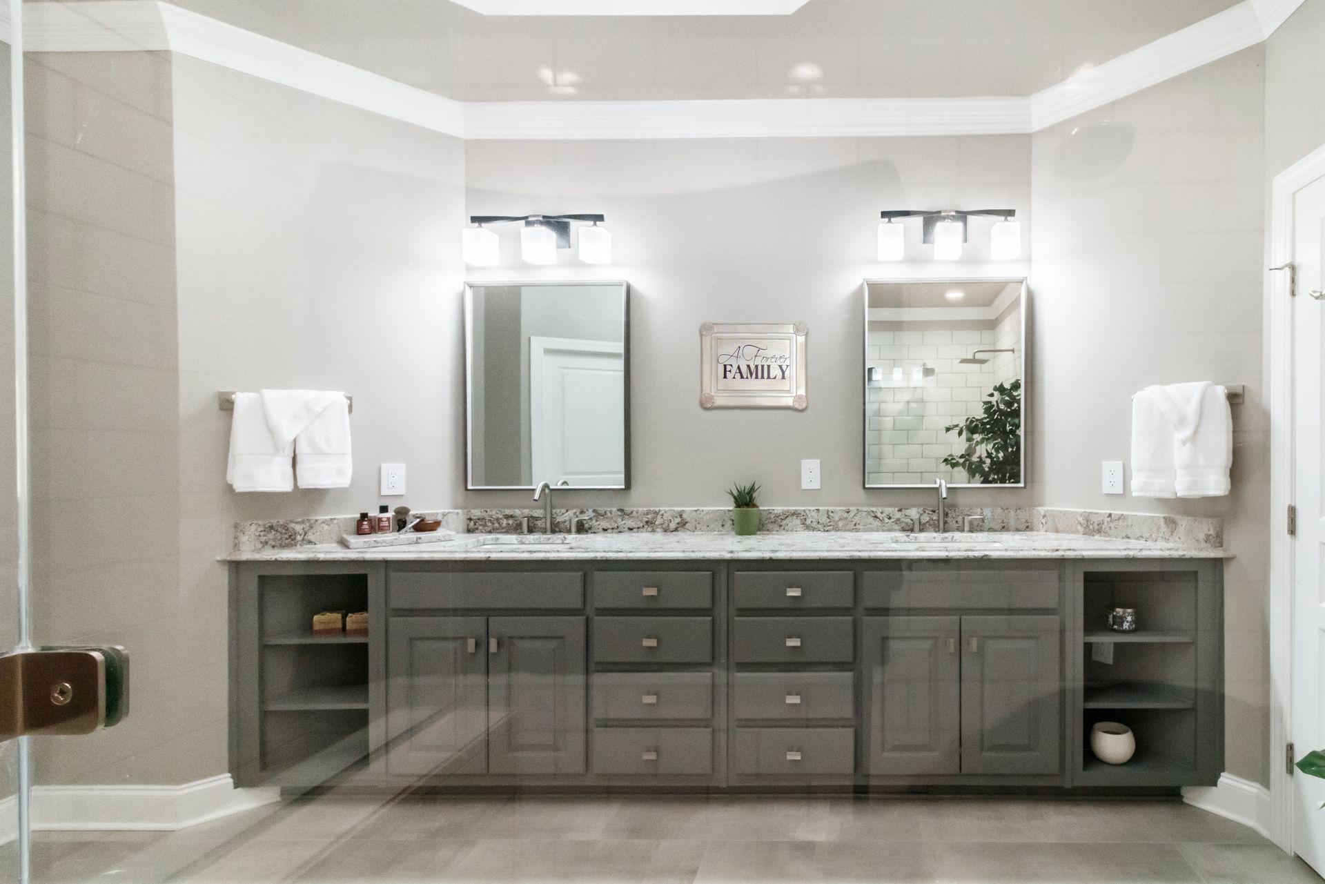 Modern bathroom with double vanity, gray cabinets, large mirrors, and wall sconces