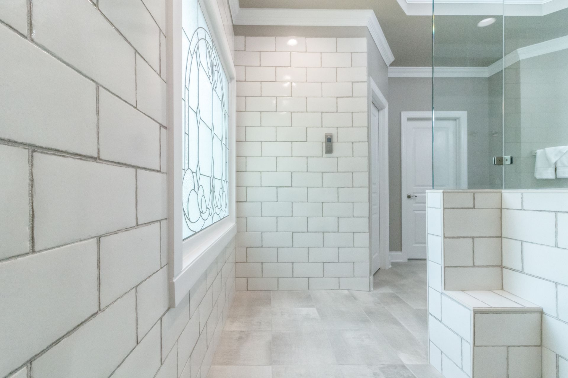 Bright white tiled bathroom with a frosted window and glass shower enclosure