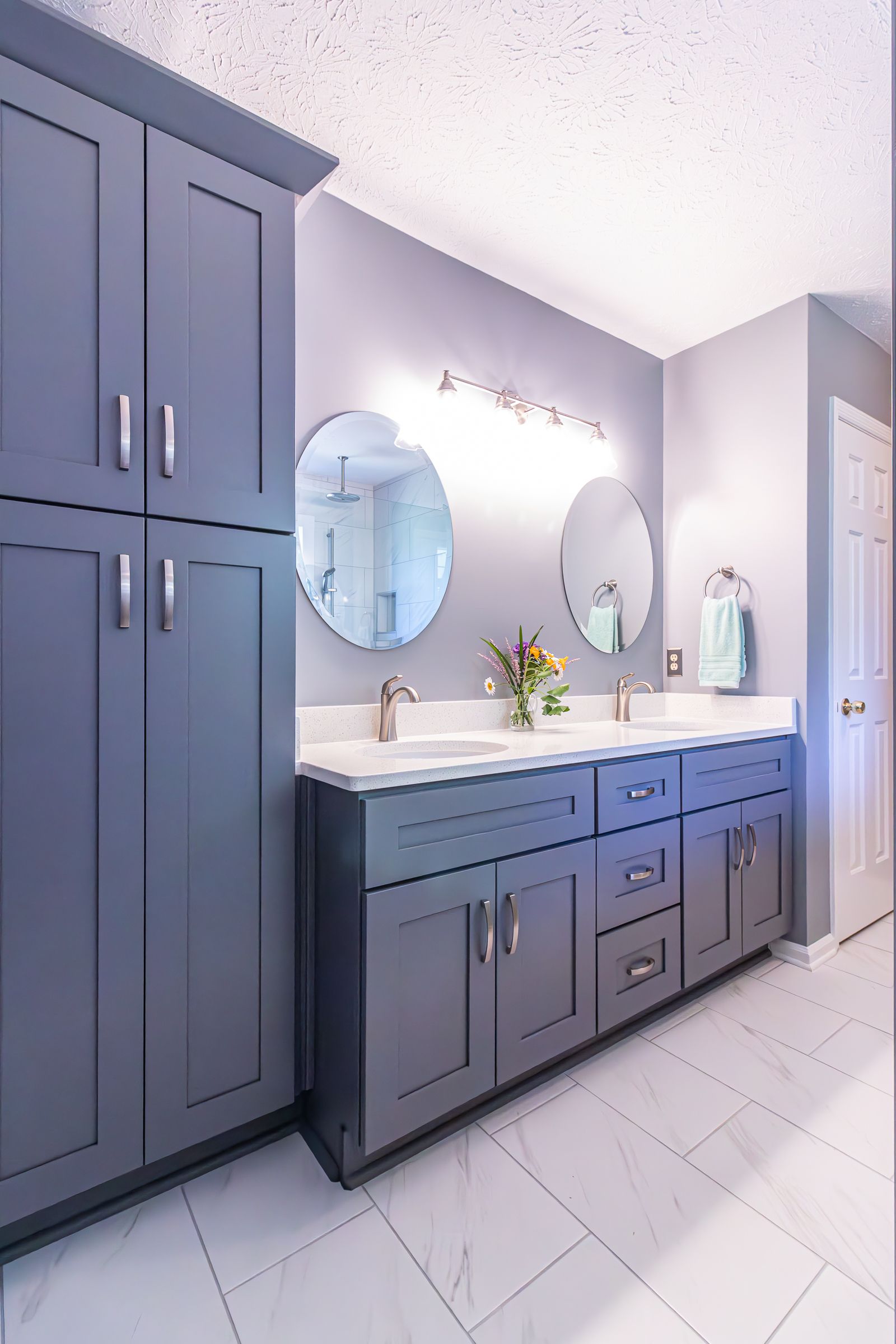 Gray bathroom with double vanity, round mirrors, and tall built-in cabinets