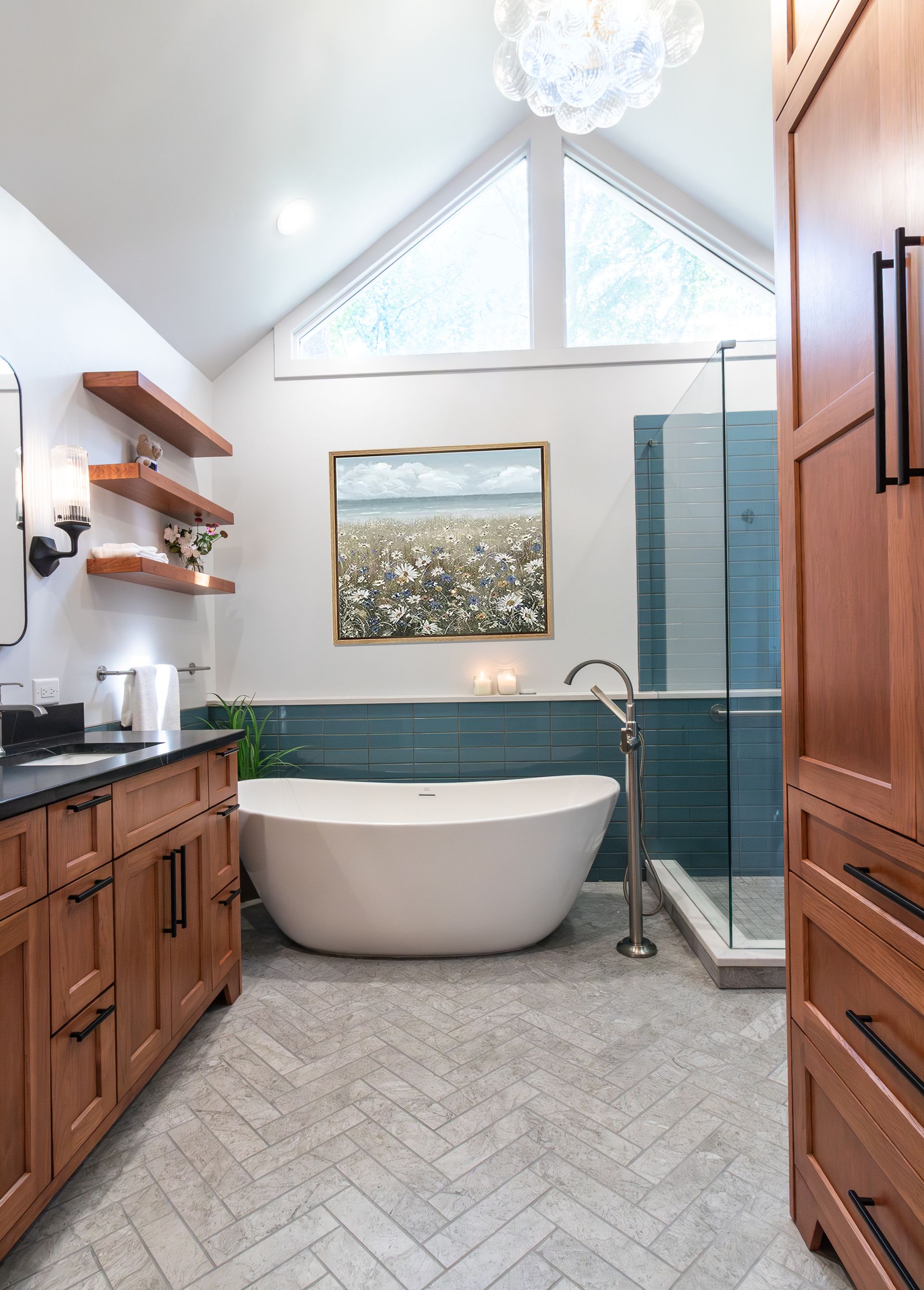 Bright bathroom with freestanding tub, walk-in glass shower, wood vanity, and chevron tile floor