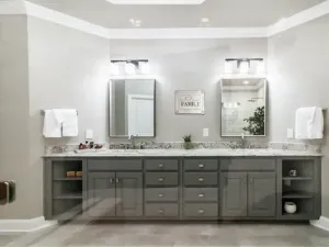 Modern double-sink bathroom vanity with gray cabinets, mirrors, wall sconces, and white countertops