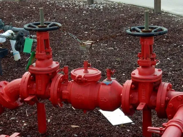 A Bunch of Red Pipes and Valves With a Green Tag on the Ground — Edwards Plumbing Pty Ltd in Chillingham, NSW