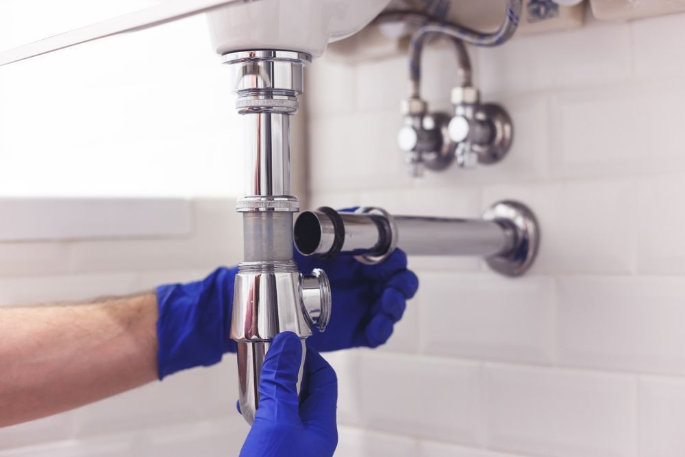 A Plumber Is Fixing A Sink Pipe In A Bathroom — Edwards Plumbing Pty Ltd in Pottsville, NSW