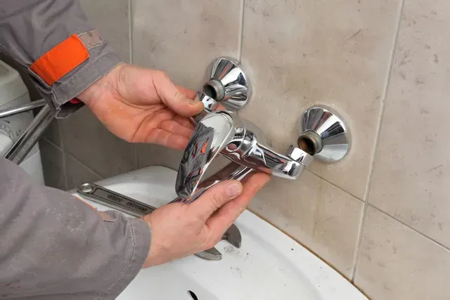 A Plumber is Fixing a Faucet in a Bathroom — Edwards Plumbing Pty Ltd in Kingscliff, NSW