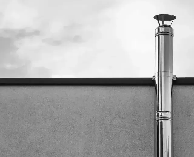 A Black and White Photo of a Chimney on the Side of a Building — Edwards Plumbing Pty Ltd in Ocean Shores, NSW