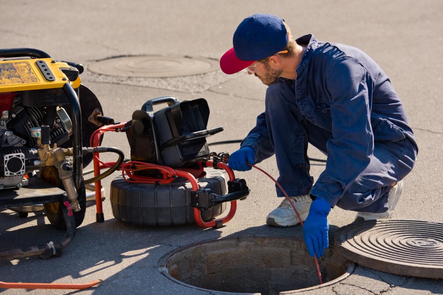 A Man is Kneeling Down in Front of a Manhole — Edwards Plumbing Pty Ltd in South Murwillumbah, NSW
