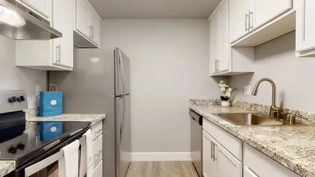 Modern kitchen with white cabinets, granite countertops, stainless steel appliances, and a sink.