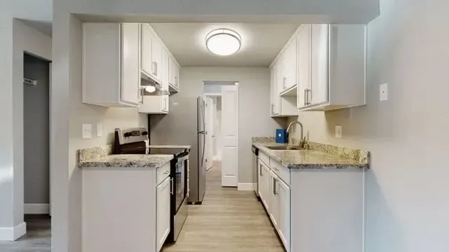 Galley kitchen with white cabinets and granite countertops.