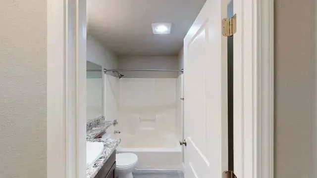 Bathroom with vanity, toilet, and bathtub/shower combo.