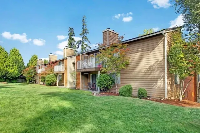 Exterior view of apartment buildings with balconies and a grassy lawn at Larch Alderwood in Lynnwood, WA.