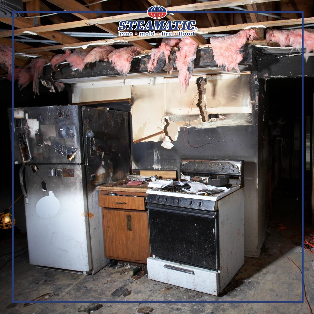 Burned kitchen with charred ceiling insulation, damaged stove, and refrigerator in a fire-damaged room