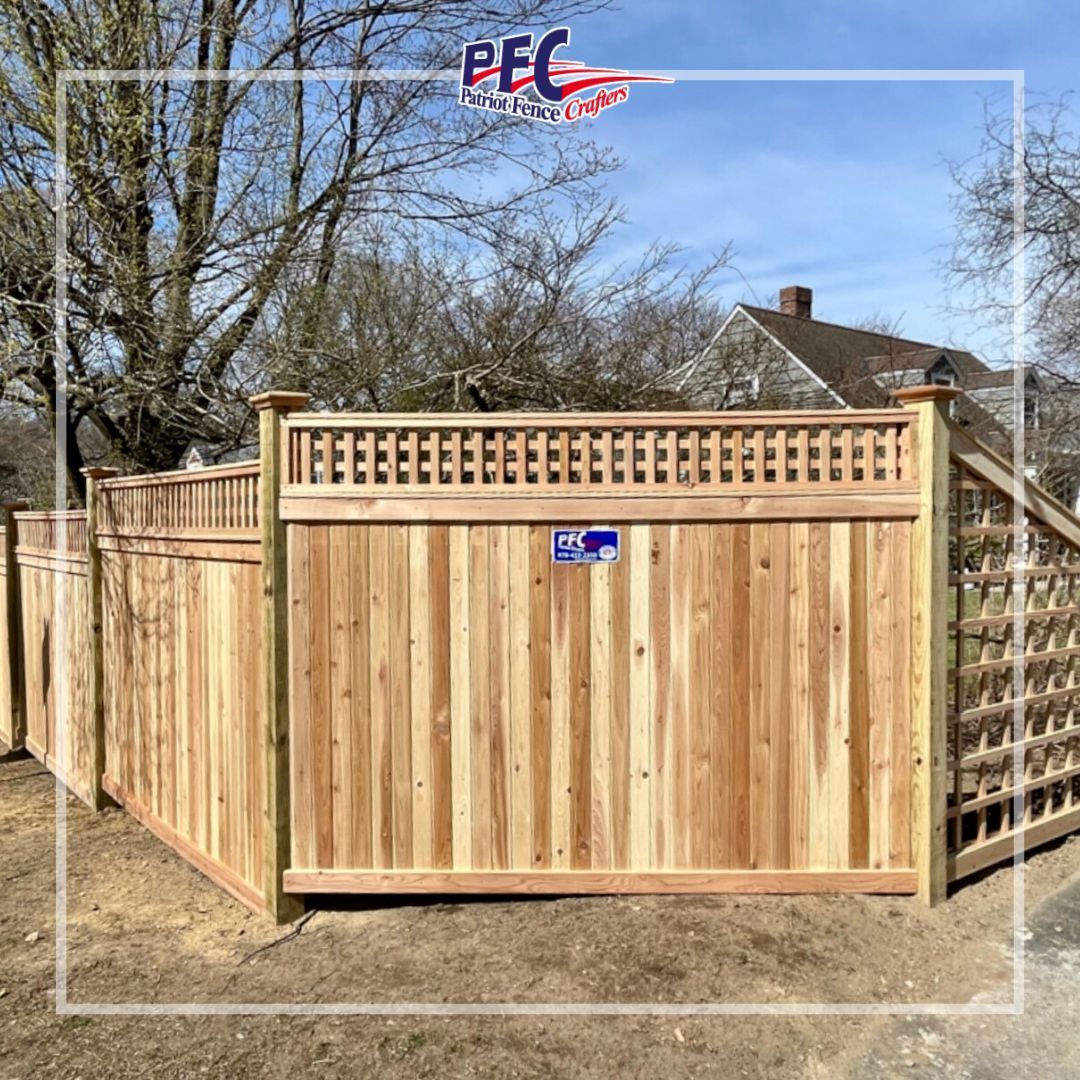 Wooden backyard privacy fence with lattice top, enclosing a yard under a clear blue sky.
