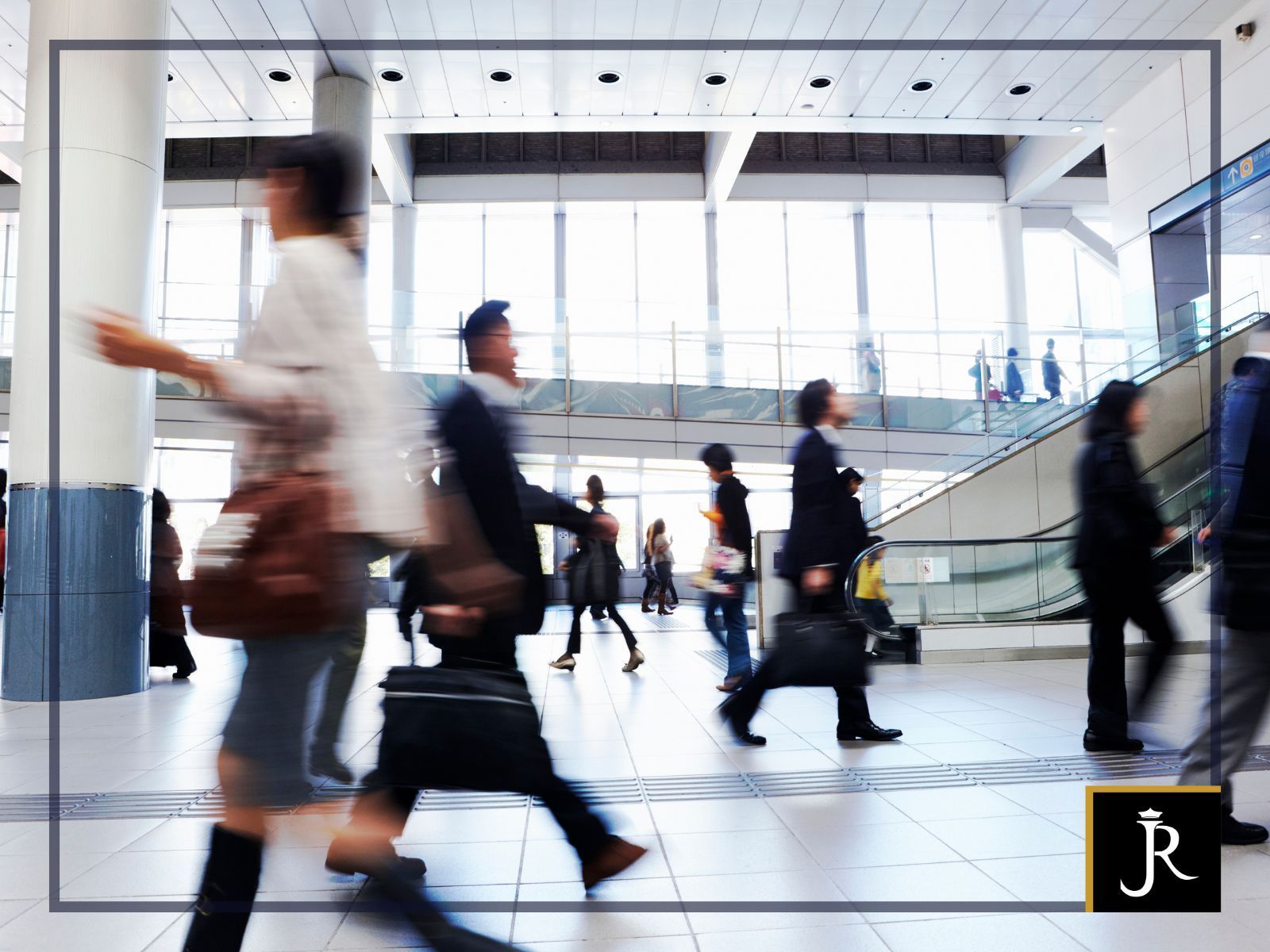 Blurred commuters walking through a bright modern office lobby with glass walls and escalator