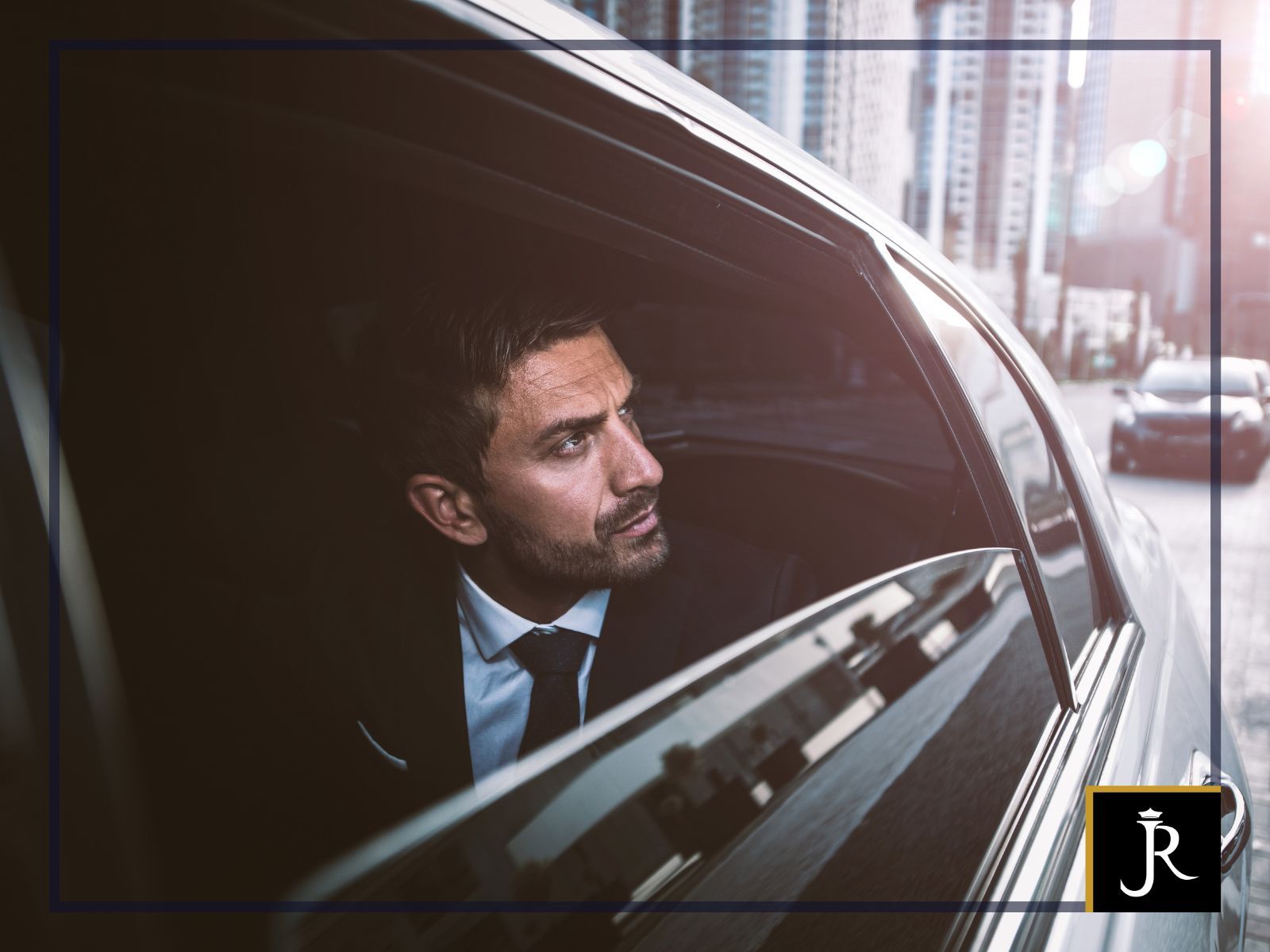 Man in a suit looking out a car window in a city street at dusk