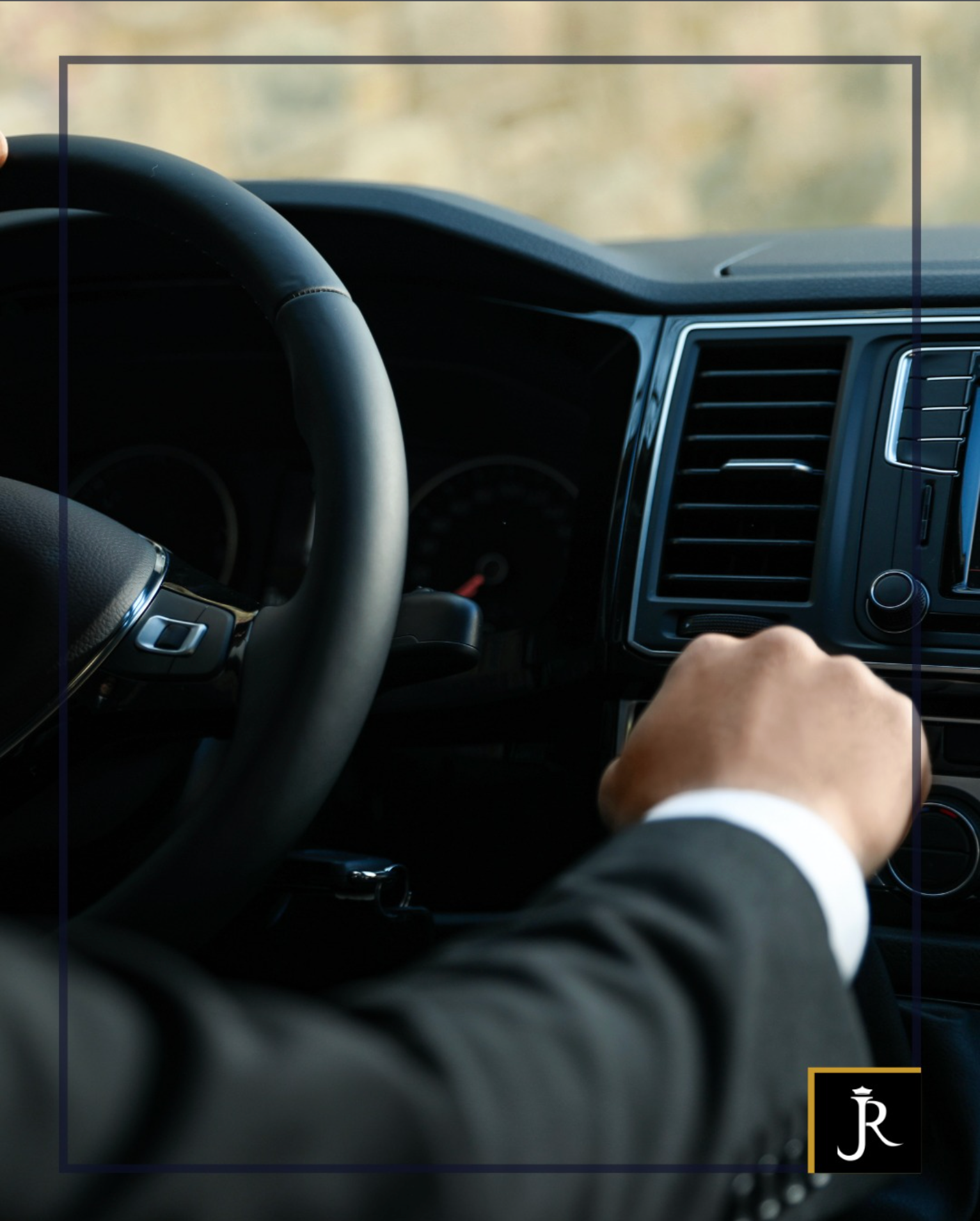 Hand on car ignition beside steering wheel and dashboard in a dark vehicle interior
