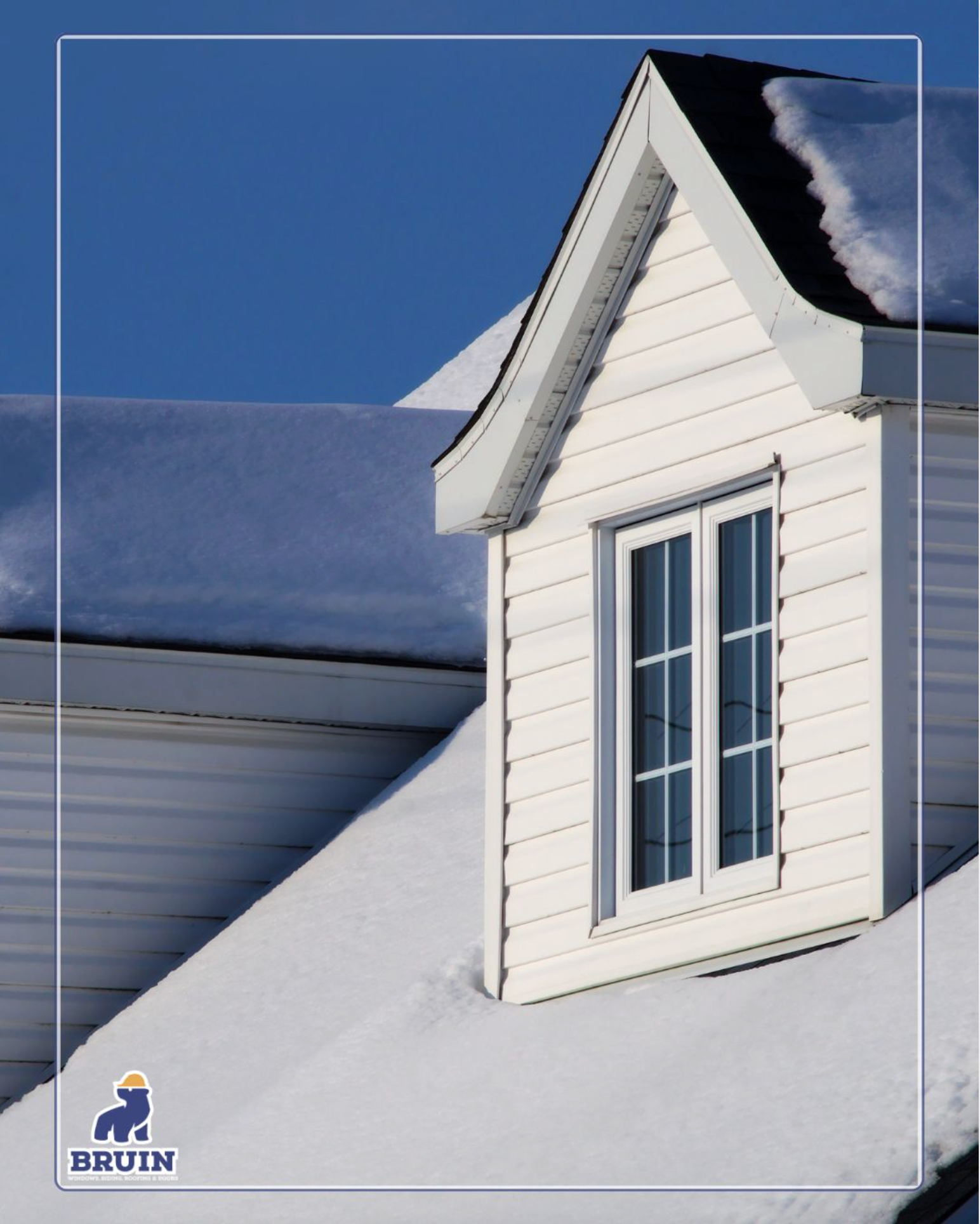 Snow-covered white house roof with a dormer window against a blue sky