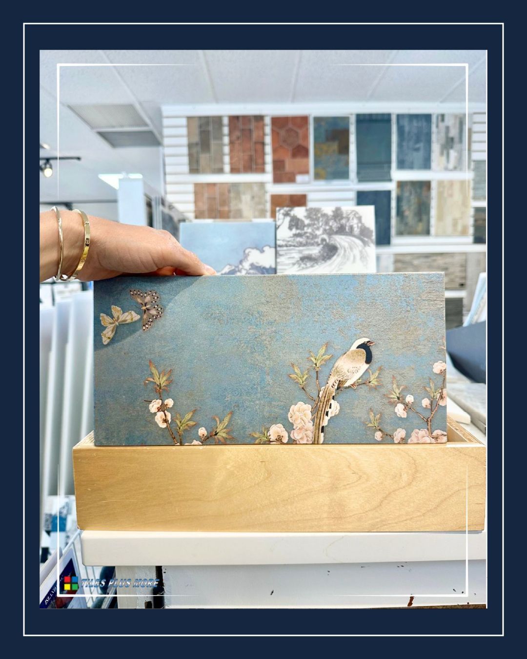 Hand holding a blue and gold decorative card in a craft store aisle with paper samples behind it