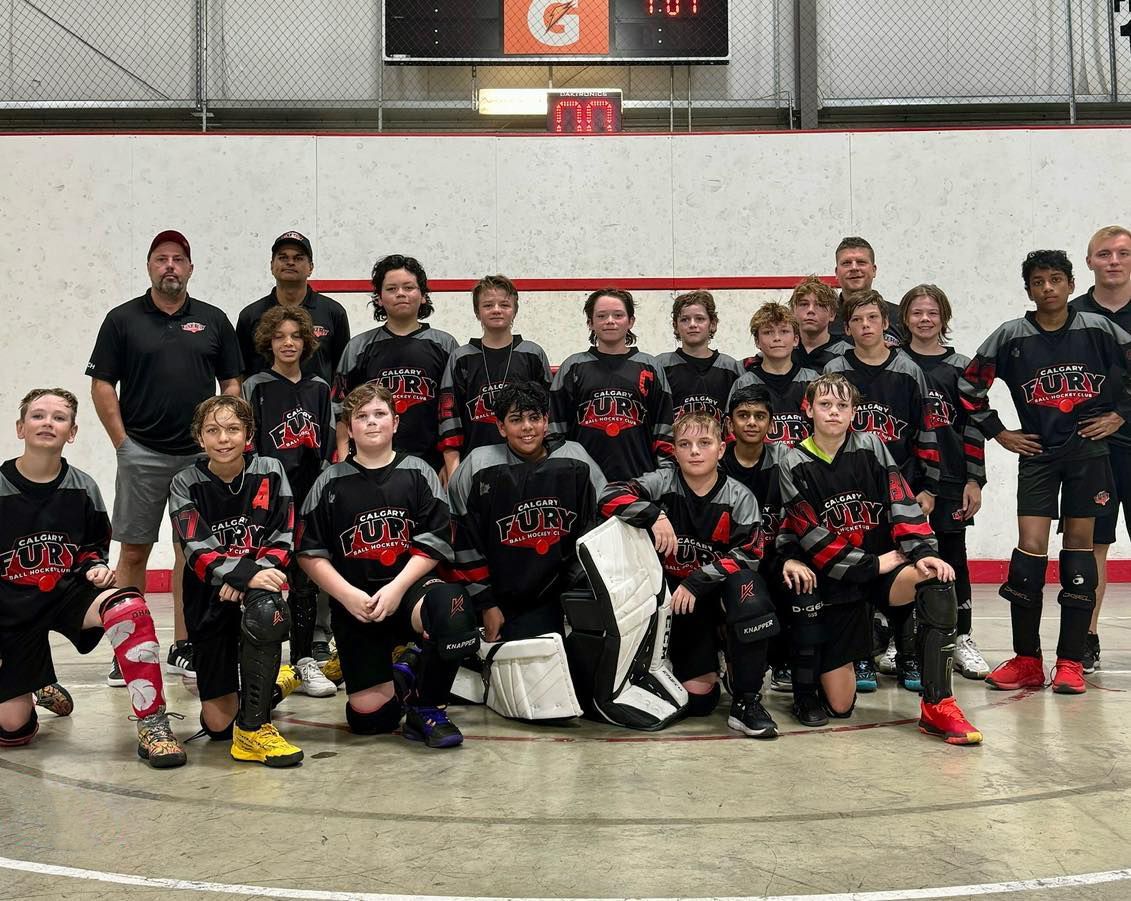 U13 Fury ball hockey team group photo wearing black jerseys after a game