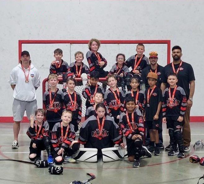 U9 Fury ball hockey team group photo wearing black jerseys after winning a medal
