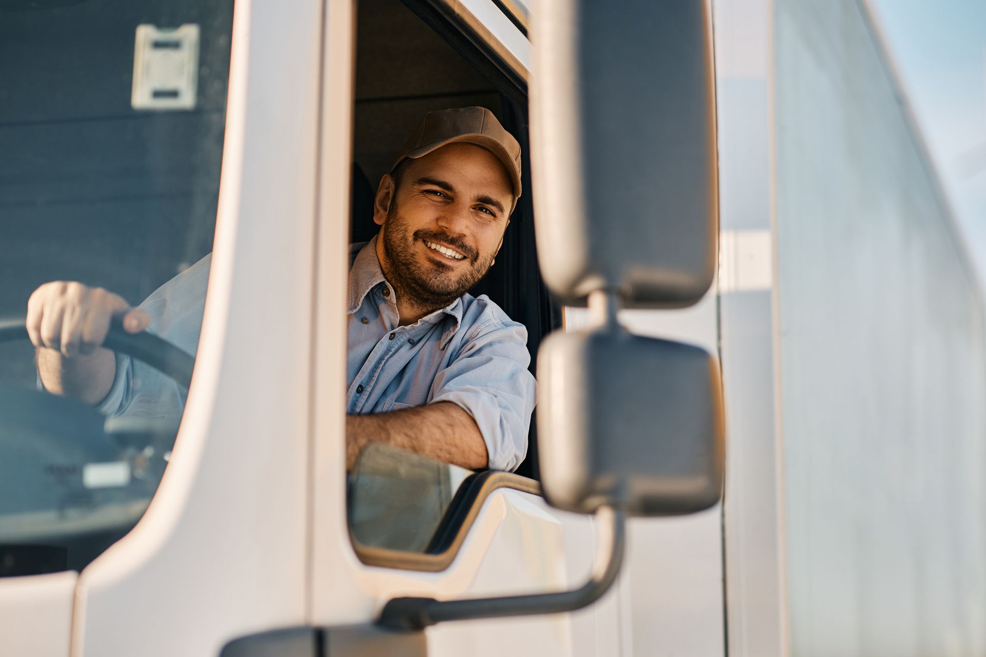 Smiling truck driver in a white truck, leaning out the window.