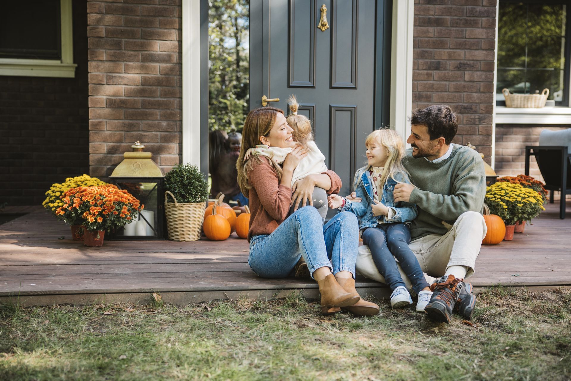 Family of four on porch steps; the children are held by their parents. Family of four on porch steps; the children are held by their parents.