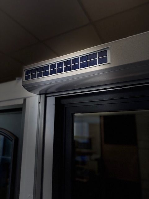 Grille d'aération rectangulaire au-dessus d'une porte coulissante en verre la nuit
