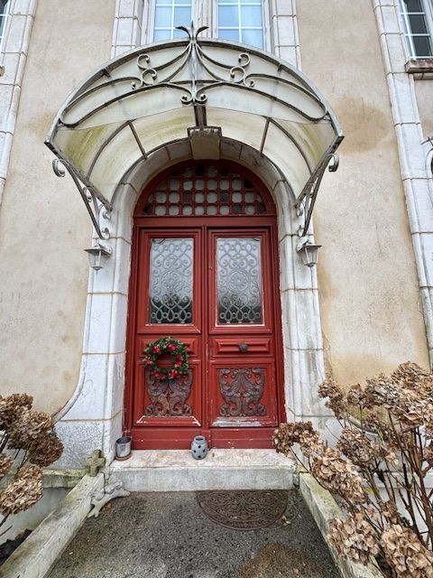Porte en bois rouge ornée sous un auvent en pierre arqué décoratif