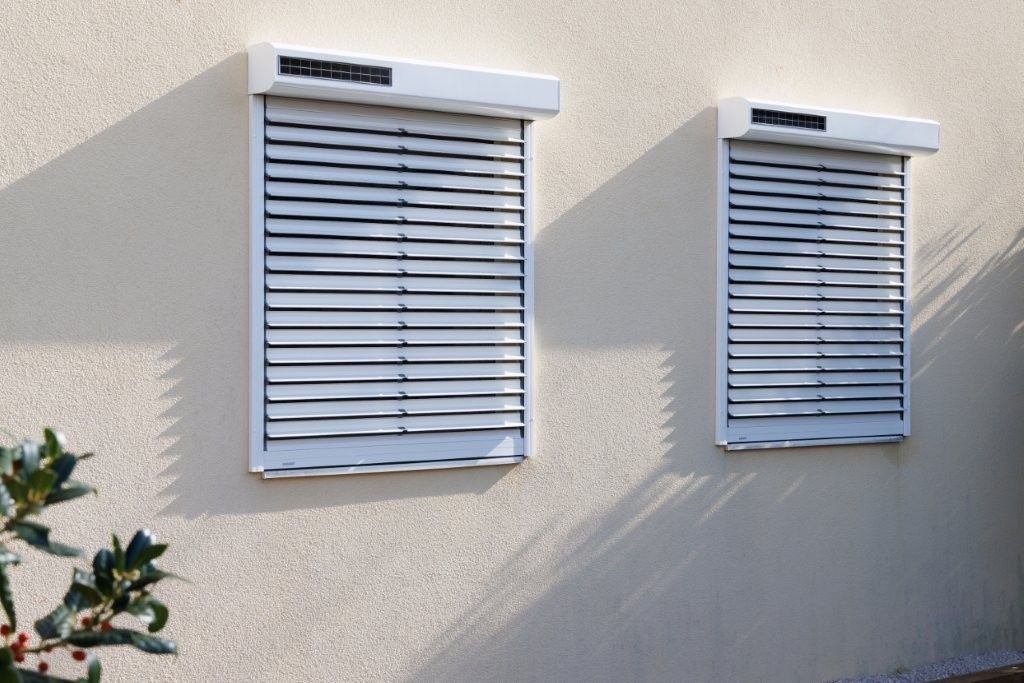 Intérieur d'entrepôt vide avec sol en béton, poutres en bois et hautes fenêtres donnant sur les champs environnants.