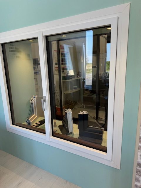 Fenêtre intérieure donnant sur une pièce aux murs turquoise, aux moulures blanches et aux reflets sur le verre