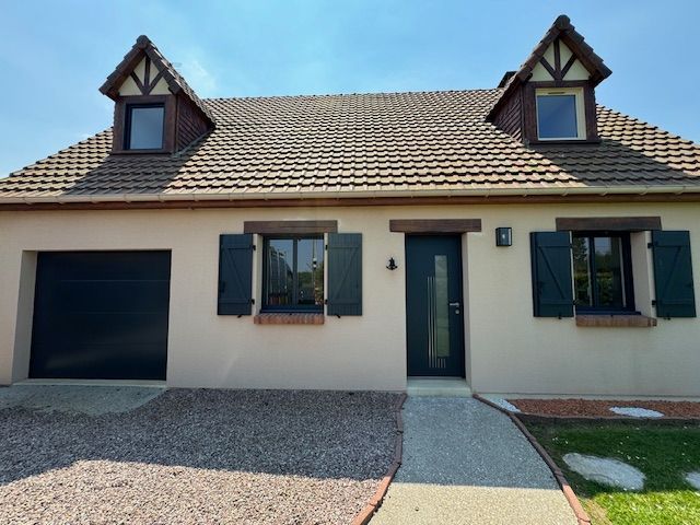 Maison de plain-pied beige avec volets foncés, garage, allée gravillonnée et toit en tuiles