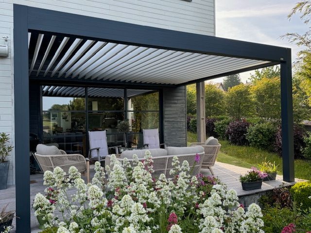 Terrasse moderne dans le jardin avec pergola noire, sièges extérieurs et parterres fleuris