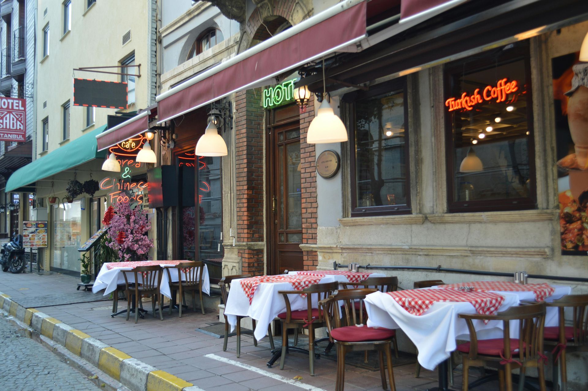 Terrasse d'un café avec des tables à damier rouge et blanc le long d'une rue étroite de la ville