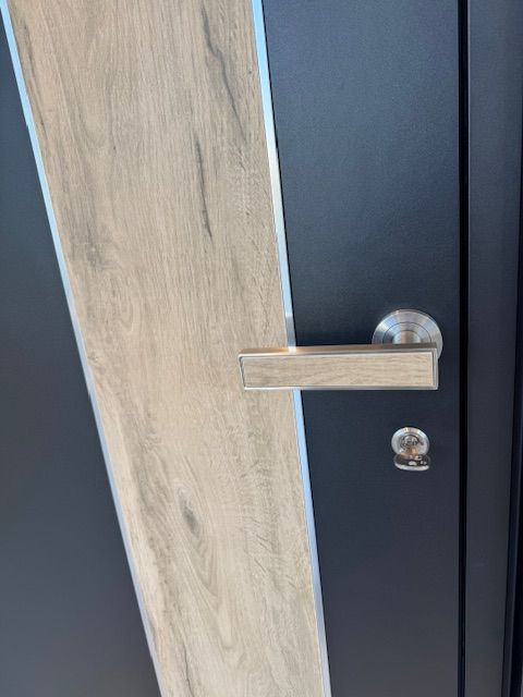 Porte moderne avec panneaux foncés et bande claire imitation bois, dotée d'une poignée horizontale argentée et d'une serrure ronde.