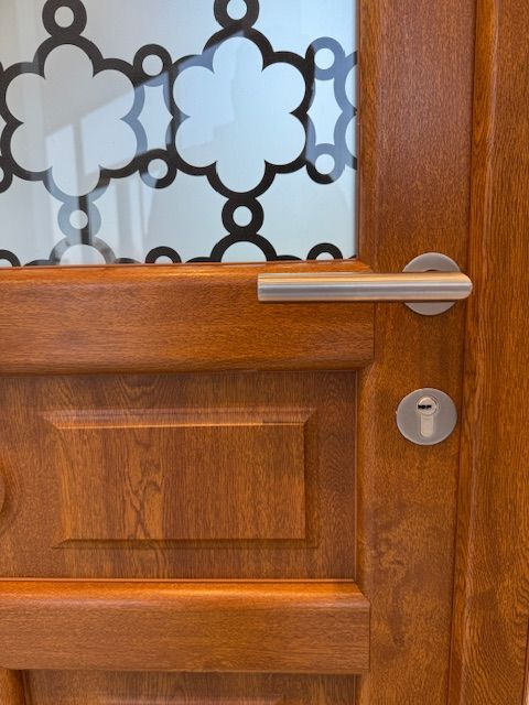 Porte d'entrée en bois avec vitres dépolies, poignée argentée et serrure.