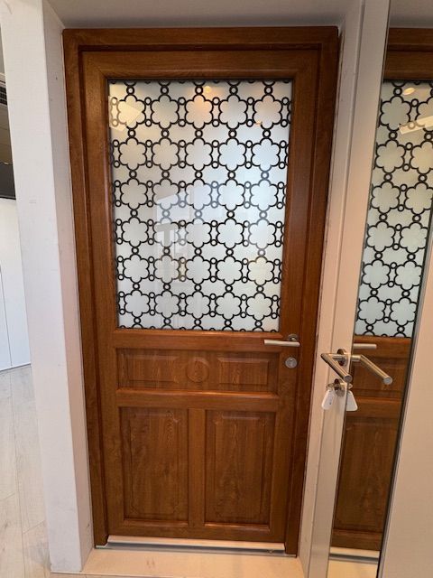 Porte en bois avec panneaux de verre dépoli à motifs dans un couloir.