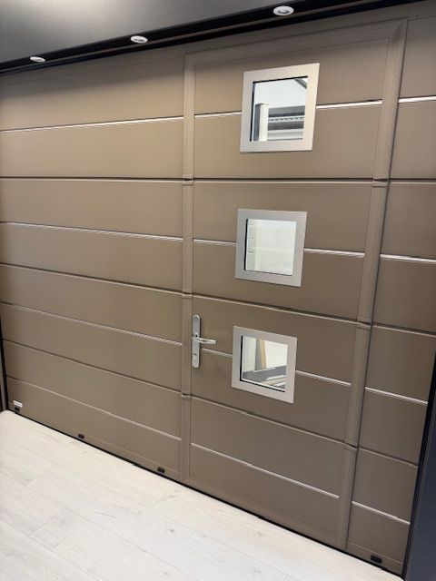 Mur marron moderne avec trois petites fenêtres carrées et une porte étroite dans un couloir