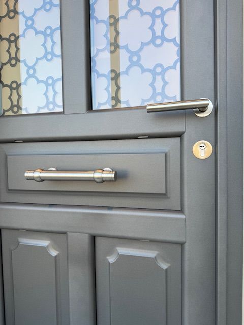 Porte d'entrée grise avec vitres, poignée argentée et fente à lettres