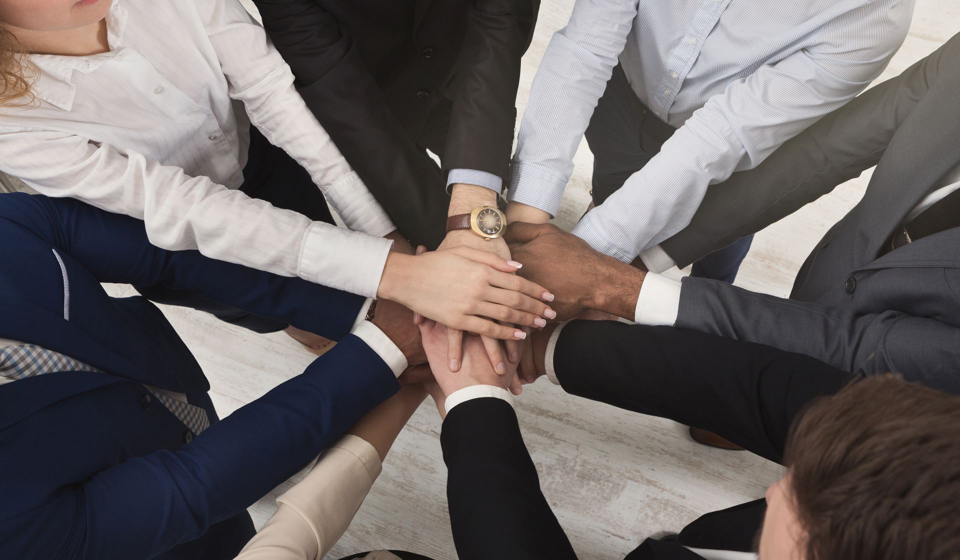 A group of people are putting their hands together in a circle.