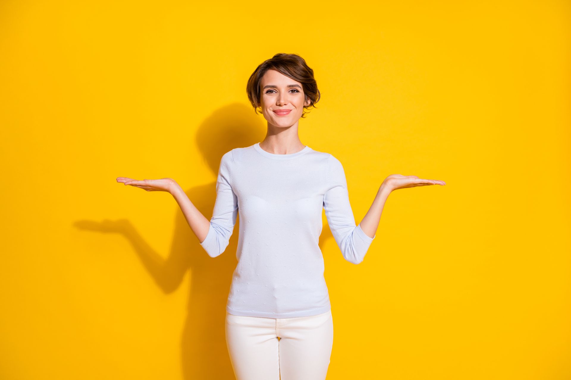 A woman is holding something in her hands on a yellow background.
