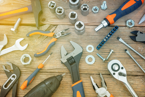 A bunch of tools are laying on a wooden table.